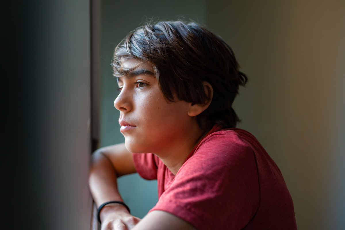 Hispanic boy looking out window