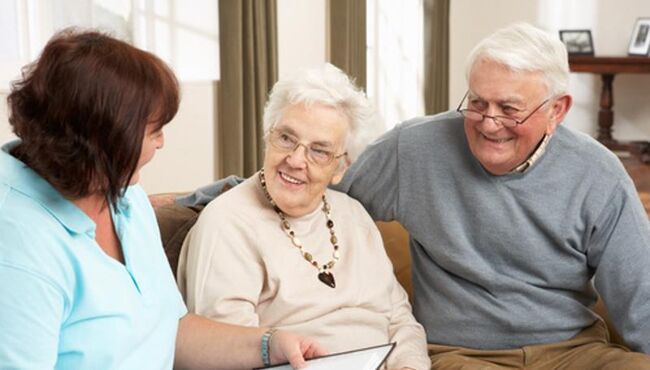 Older man and woman talking to younger woman holding information booklet
